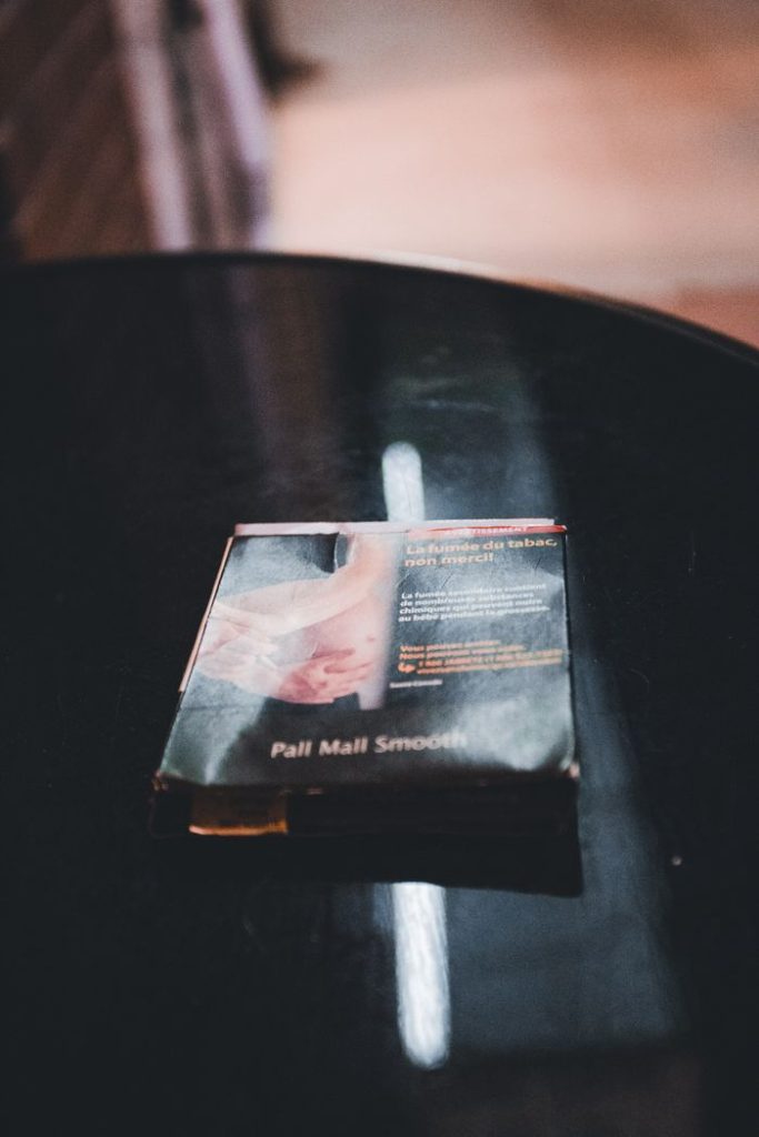 Close-up still life of a cigarette pack on a black table in a dimly lit room.