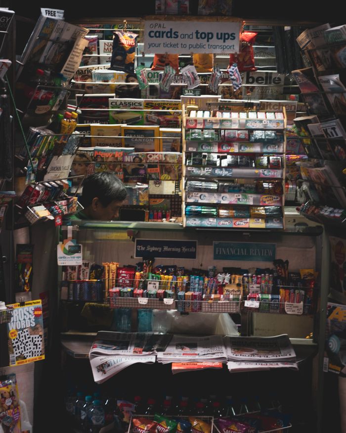 Vibrant newsstand filled with magazines, snacks, and sundry items in a busy urban setting.