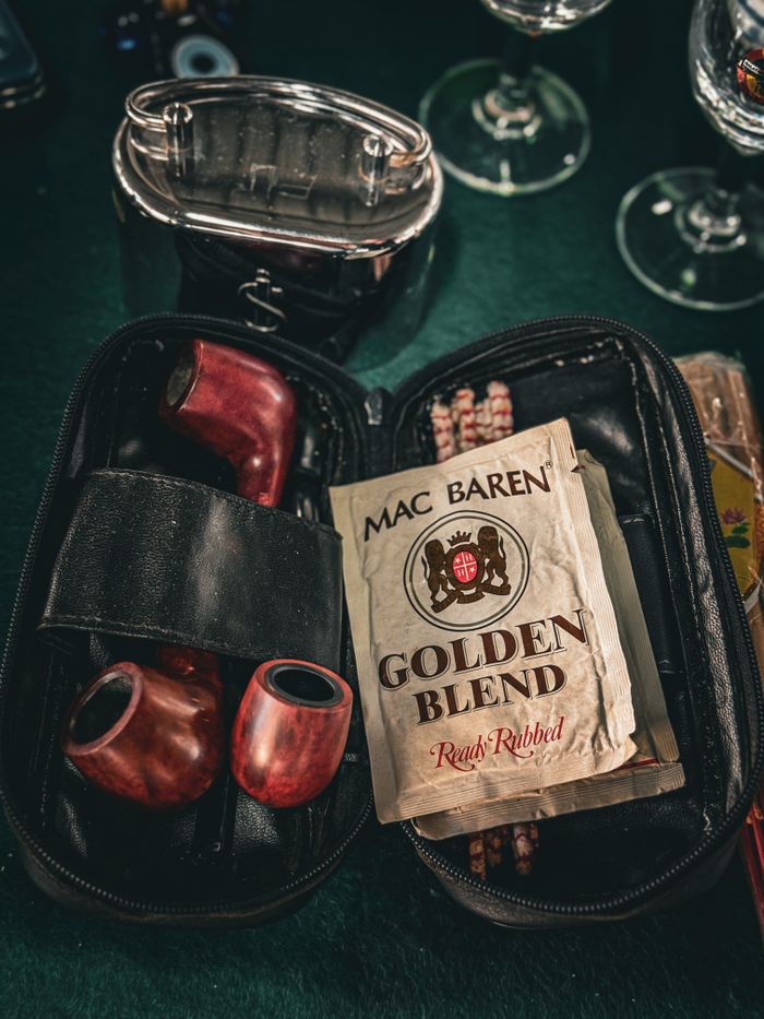 Vintage smoking accessories with Mac Baren Golden Blend tobacco on a dark table.