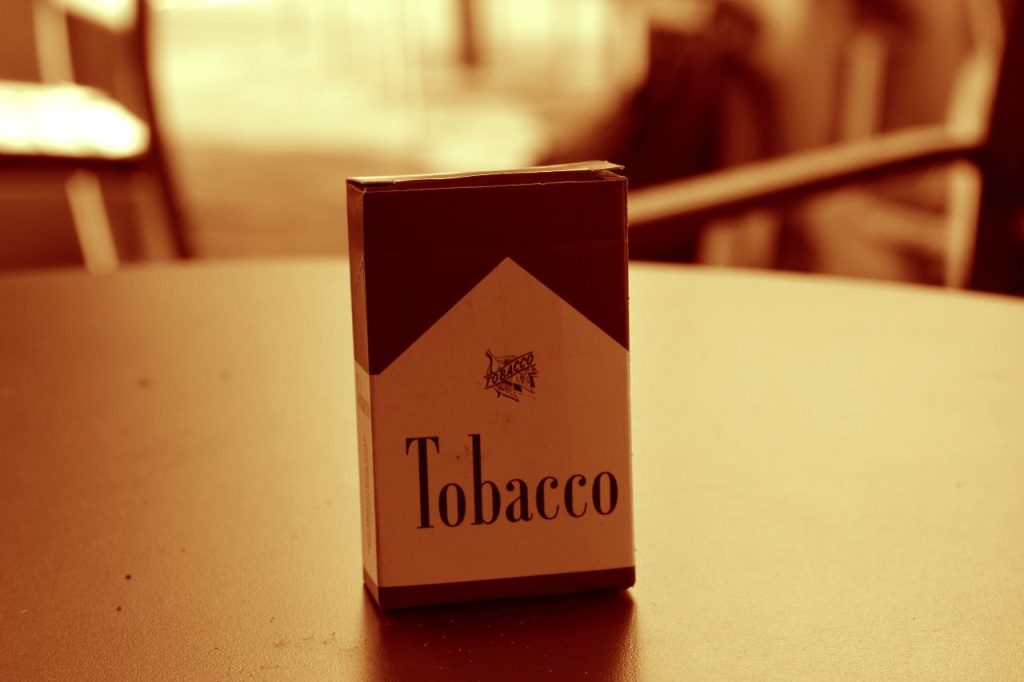 Close-up of a vintage-style tobacco pack on a table, captured with a sepia tone for a classic look.