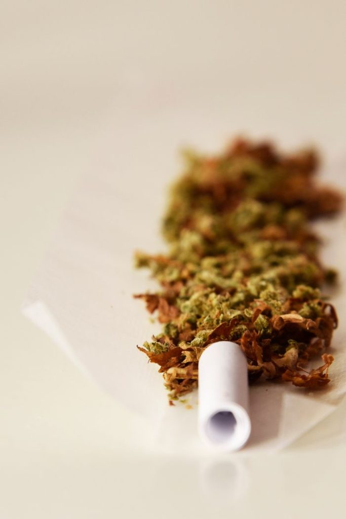 A close-up view of cannabis and tobacco mixture on rolling paper, ready for use.