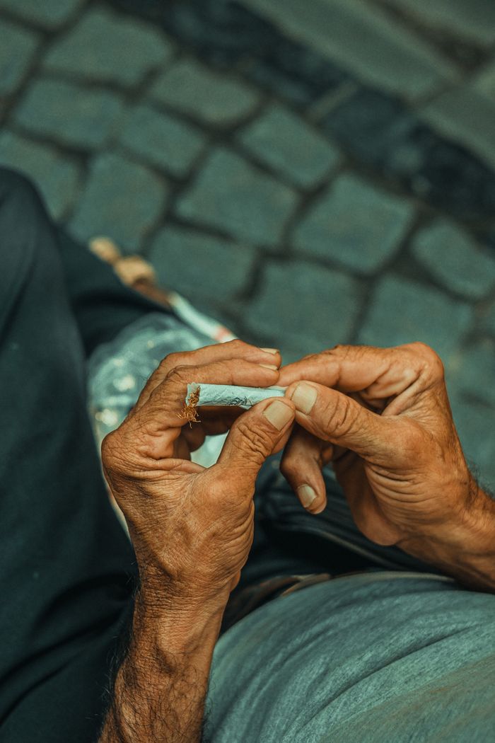 Detailed close-up of elderly man's hands skillfully rolling a cigarette on an Istanbul street.