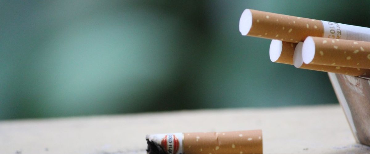 Cigarette with ashes on surface, highlighting tobacco use and health risks.